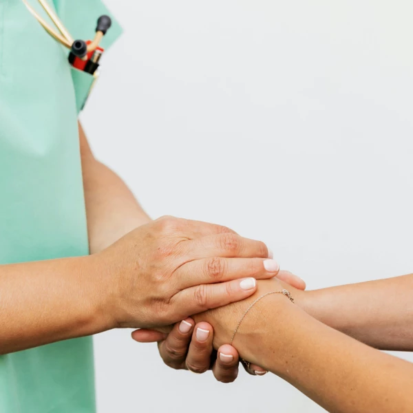 Nurse holding patient's hand during daily visit to monitor healing and ensure comfort at Naghoi.