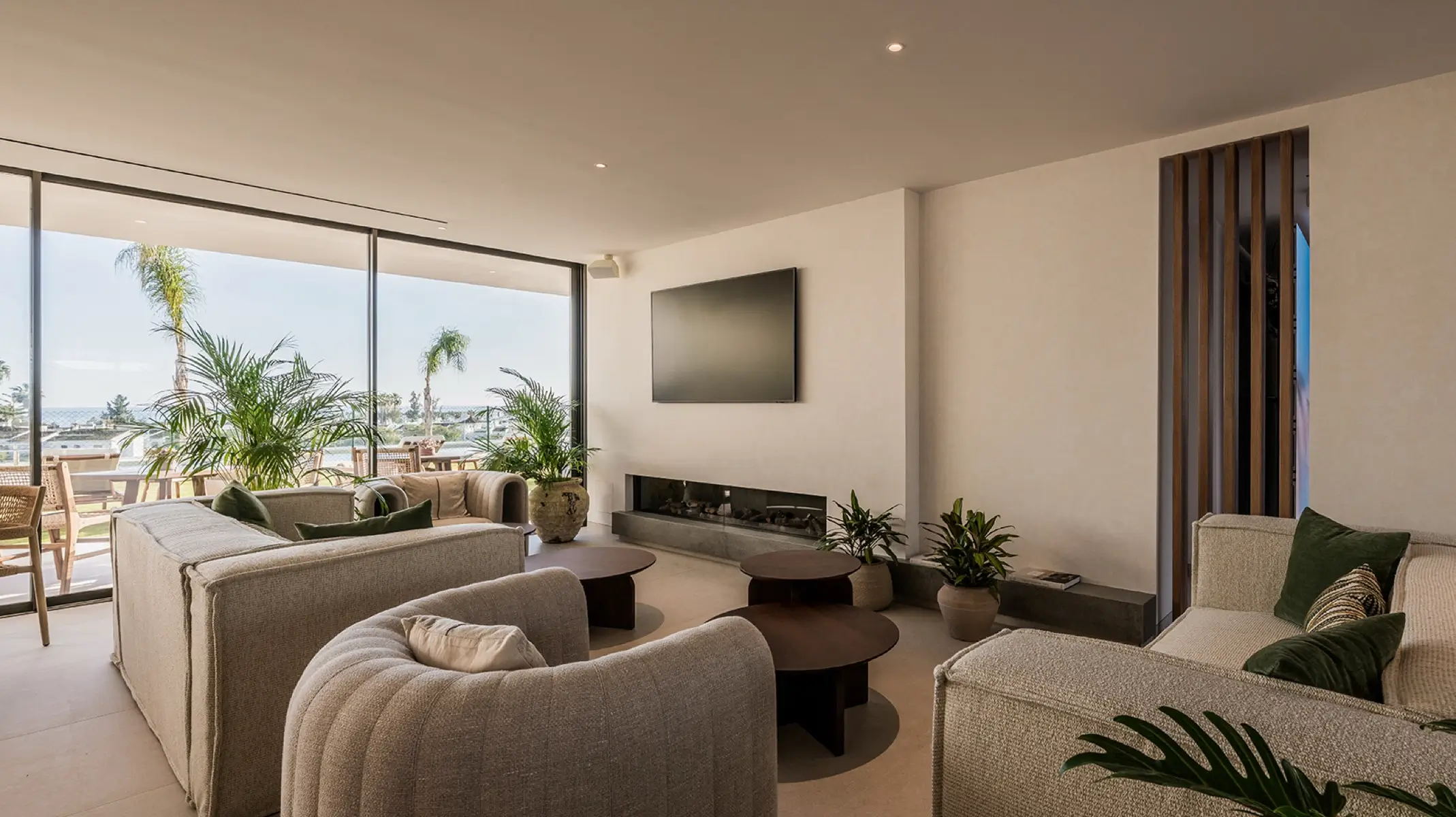 Naghoi communal lounge — floor-to-ceiling windows with sea view, fireplace and comfortable seating, post-operative recovery facility Marbella.