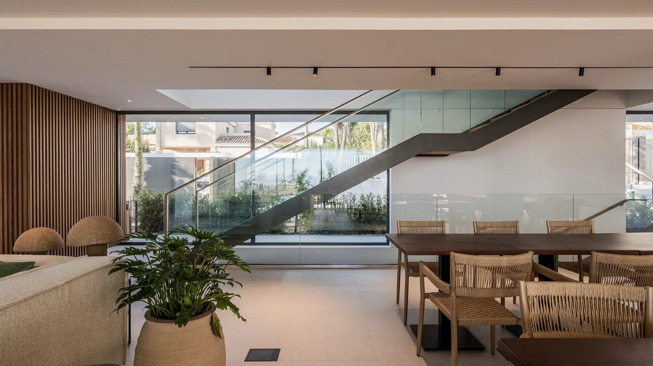 Naghoi communal dining area — open-plan interior with a glass staircase and garden views within Facialteam’s healing sanctuary.