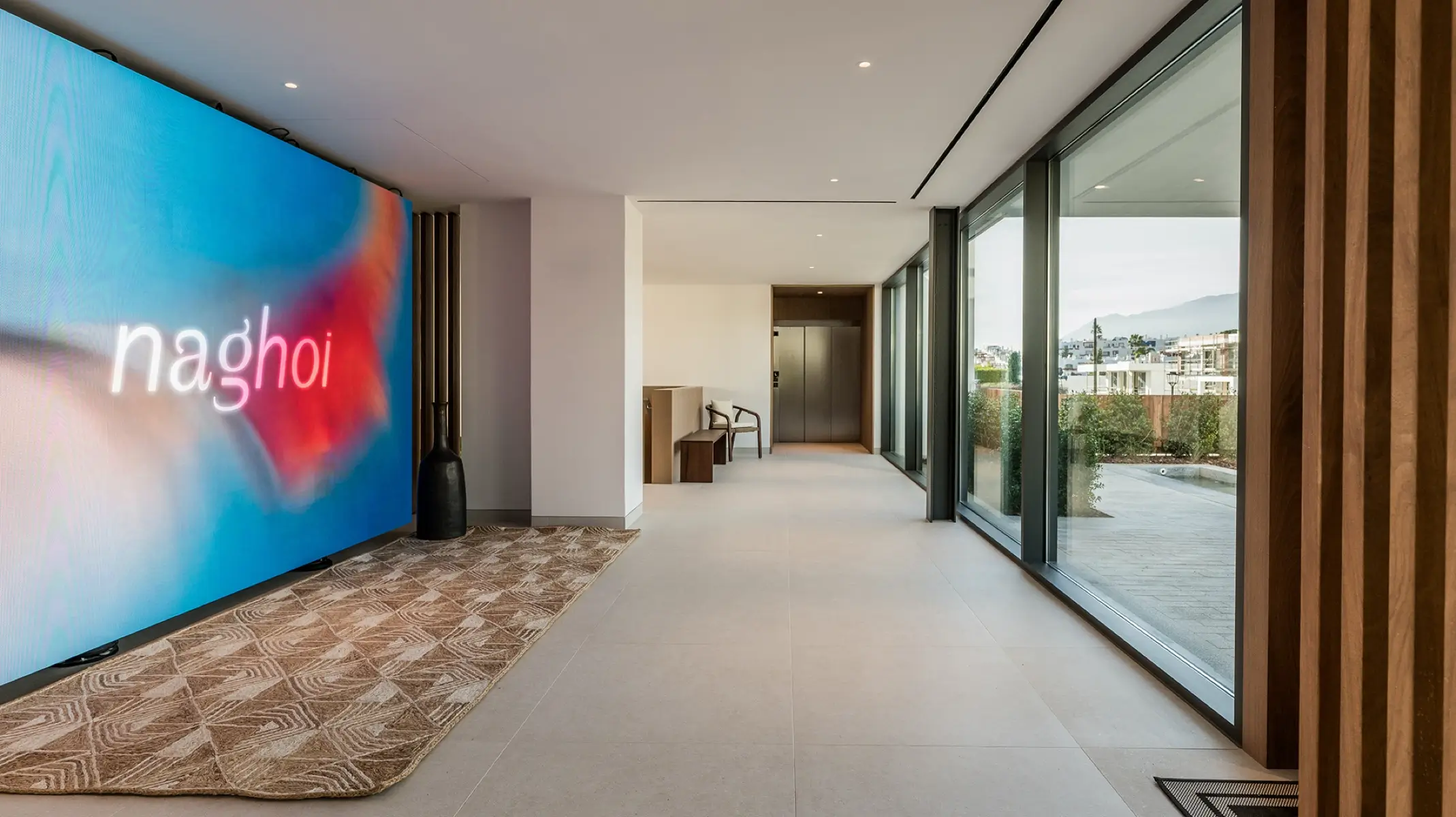 Naghoi entrance lobby — modern interior with floor-to-ceiling windows overlooking the gardens at Facialteam’s recovery sanctuary in Marbella